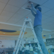 Man on ladder lifting up drop ceiling panel with AP