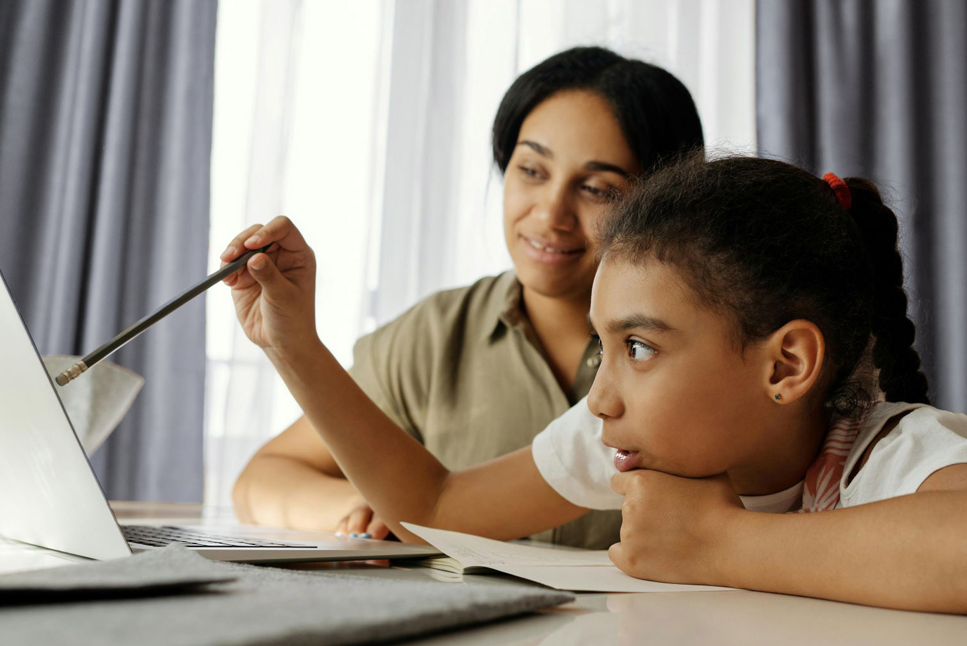 woman and girl at desk looking at laptop screen